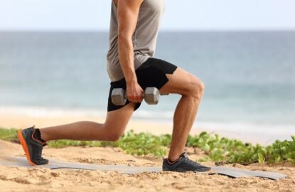 Lunge leg workout with dumbbells weights. Fitness man doing lunges training legs on beach summer outdoors with weight.