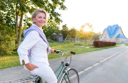 old people, leisure and lifestyle concept - Portrait of senior woman 60-65 years old on bicycle. Older lady riding city bike in european town. Smiling old female cycling with her bike in summer time